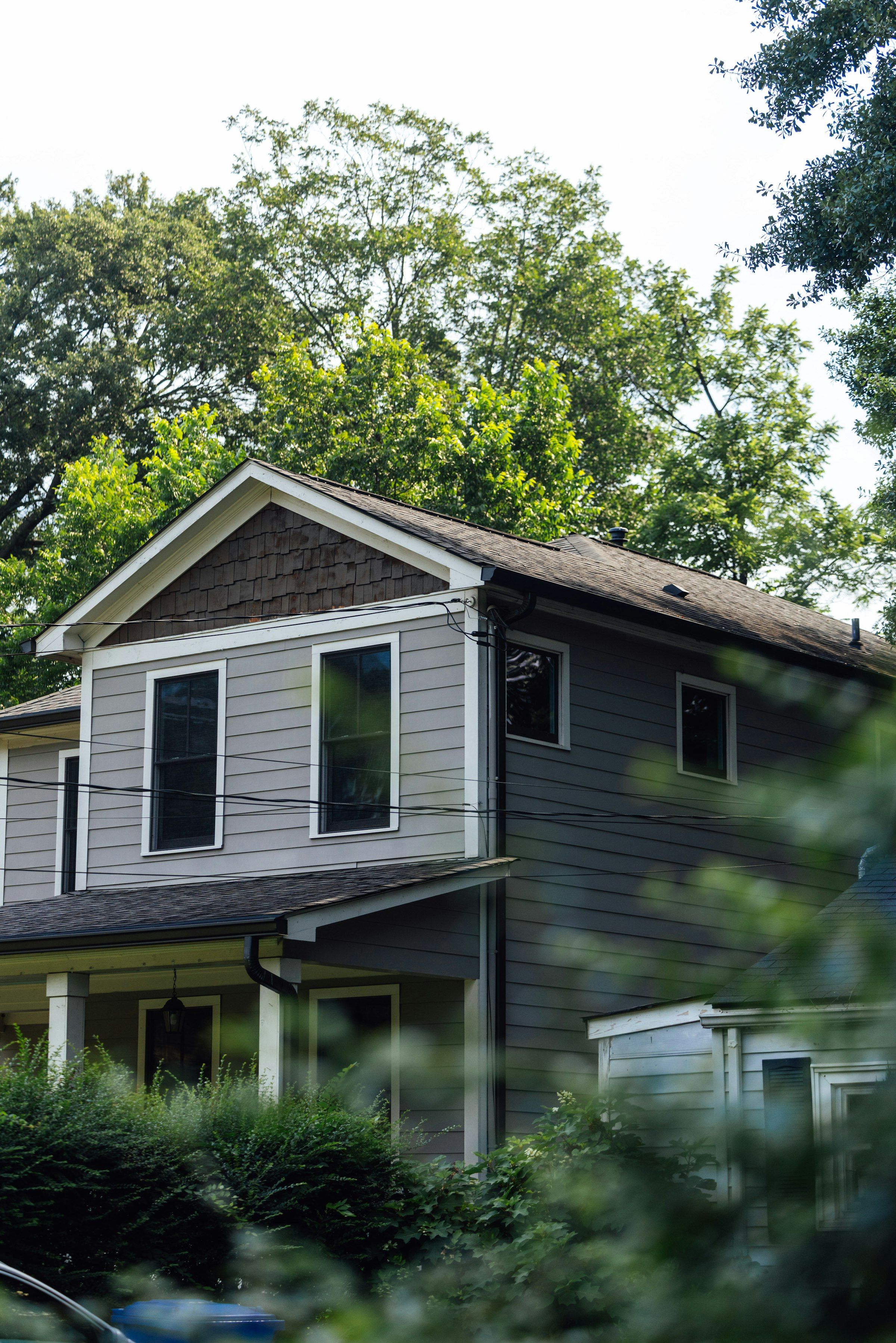 Gray two-story house surrounded by trees