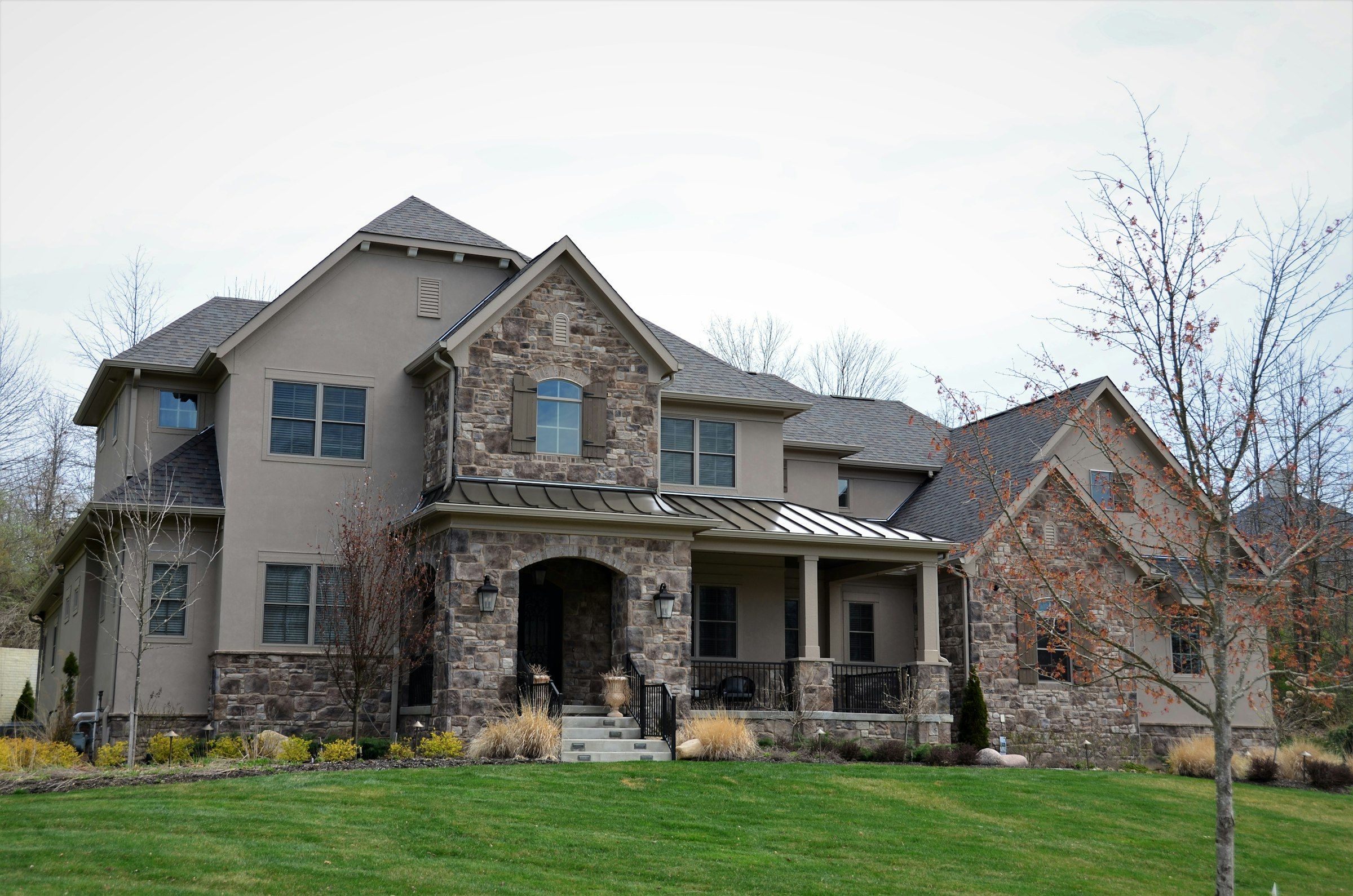 Stone two-story home with a finished architectural shingle roof and many gables